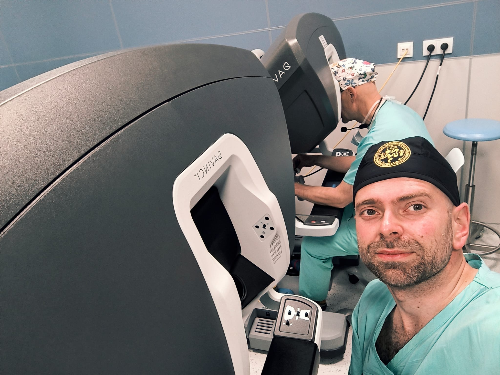 Dw&oacute;ch mężczyzn przy robotach medycznych, w strojach medycznych. Jeden z twarzą skierowaną do obiektywu, drugi do aparatury.